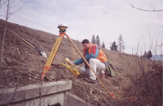 man in red jacket sitting on brown wooden ladder during daytime