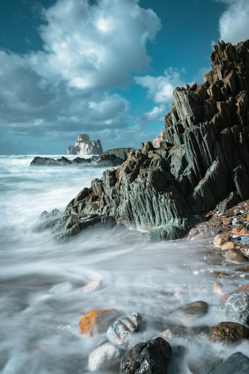 rocky shore under blue sky and white clouds during daytime