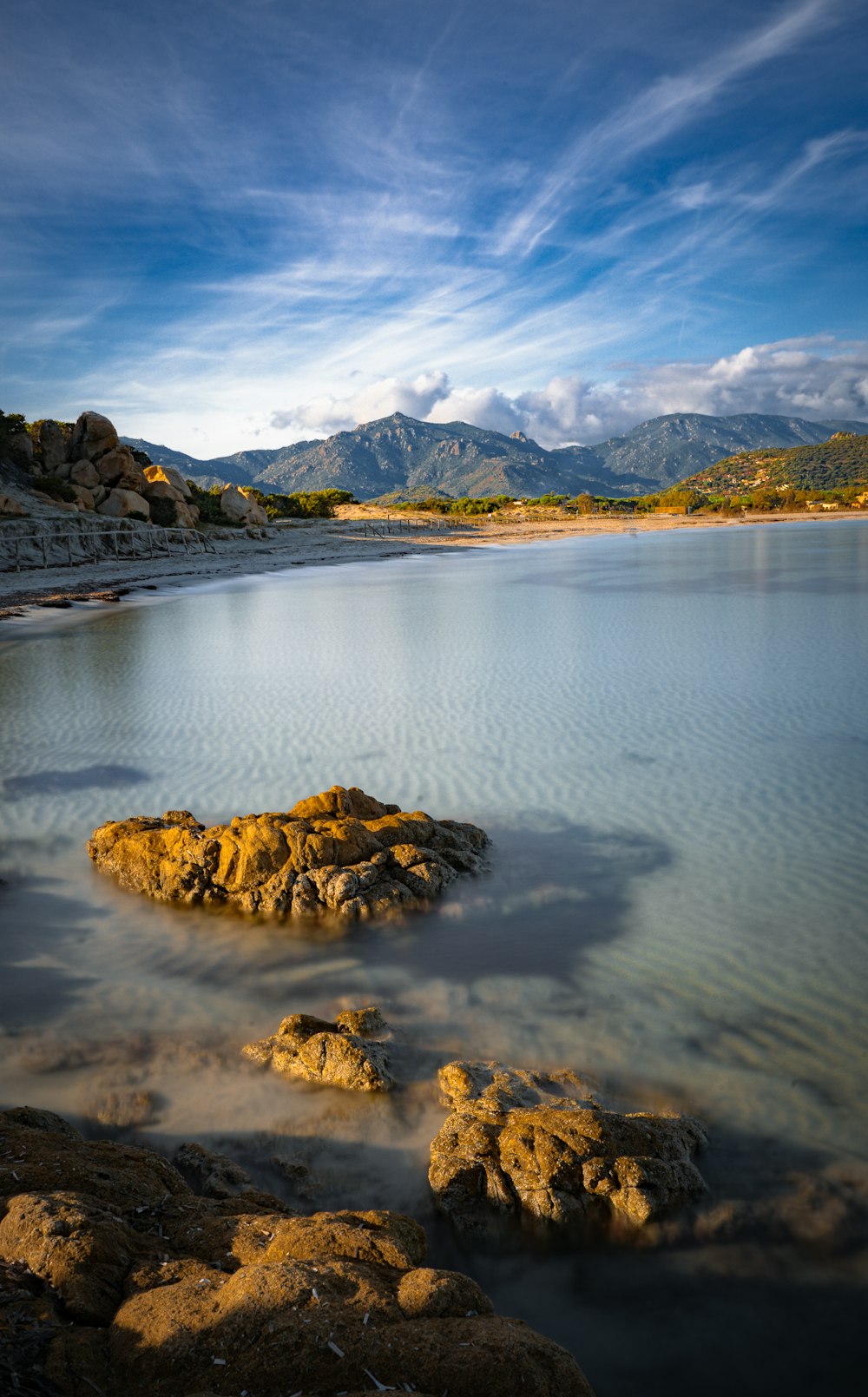 brown and black rock formation on body of water under blue sky during daytime