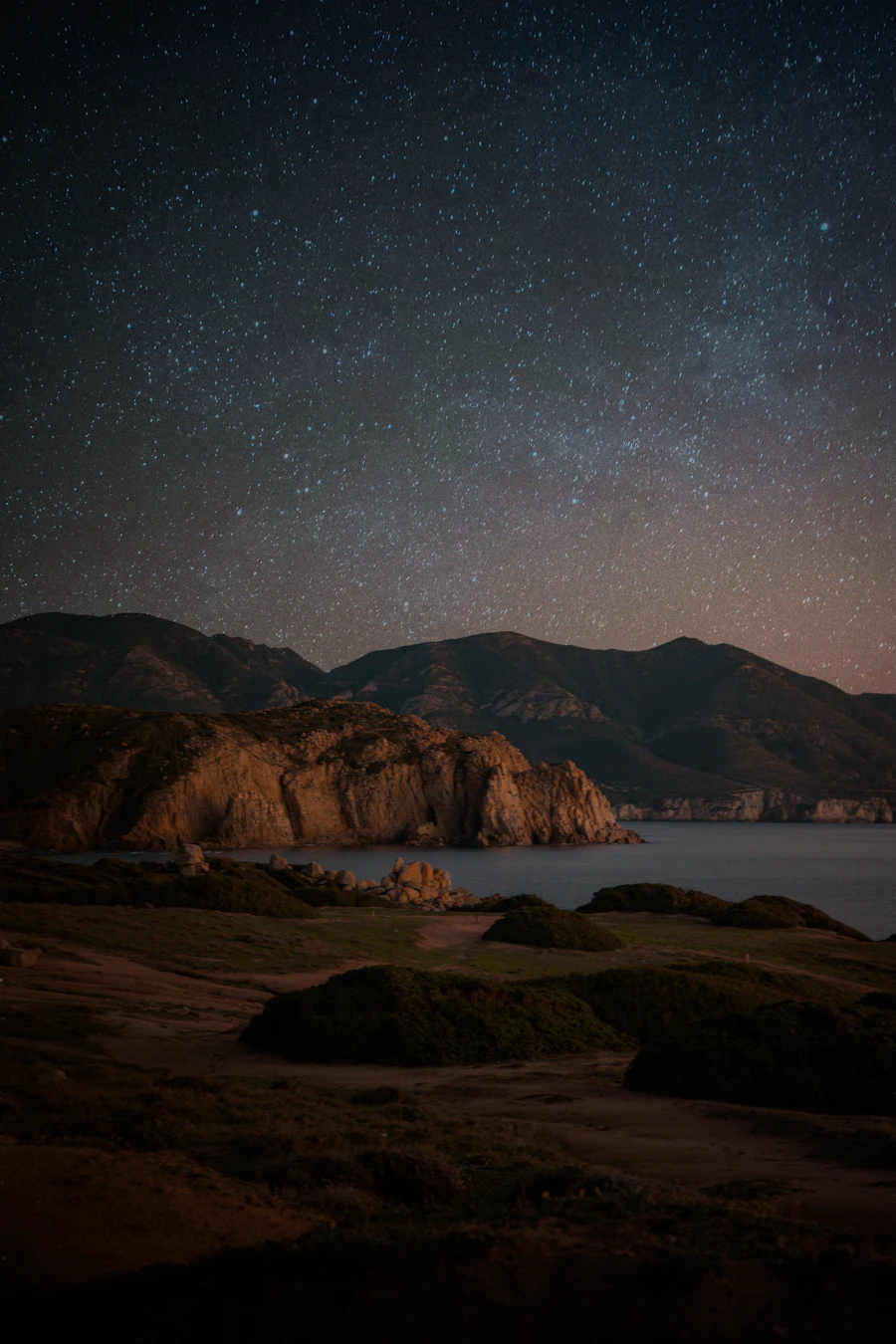 Mountains beside water beneath a starry sky
