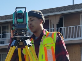 A friendly professional using a lidar scanner outdoors near a modern building.