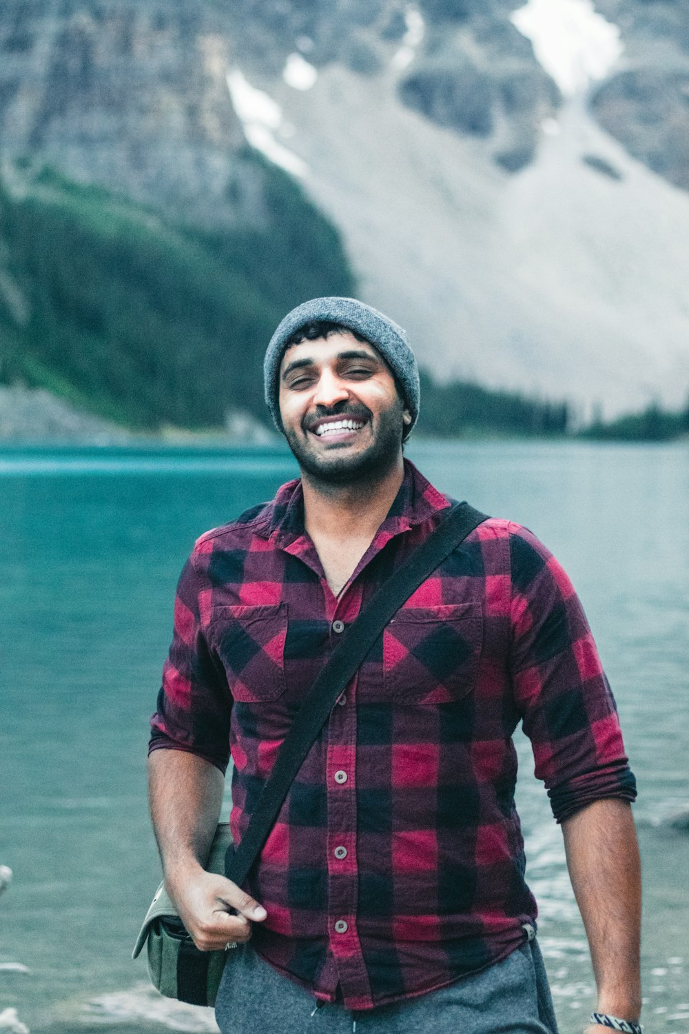 man in red and black plaid button up shirt standing near lake during daytime