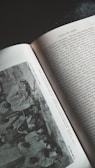 An overhead view of an open book featuring a section titled 'Races and Tribes.' The left page contains a grayscale photograph showing a group of people in traditional attire. The right page is filled with text that appears to be a narrative or historical account.