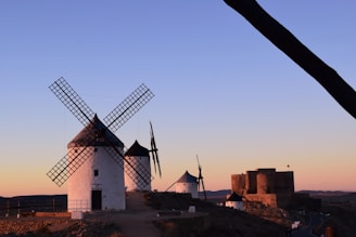A panoramic view of the iconic windmills of Consuegra at sunset, symbolizing Castilla-La Mancha's rich heritage.