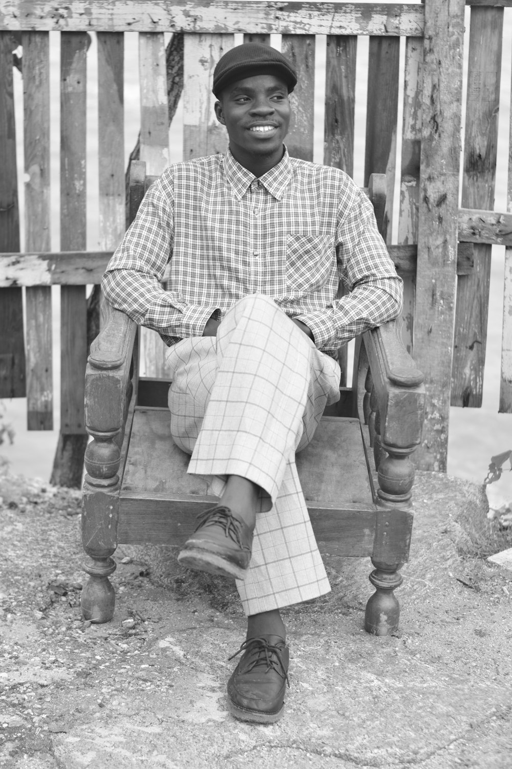 man in white and black checkered dress shirt sitting on wooden bench