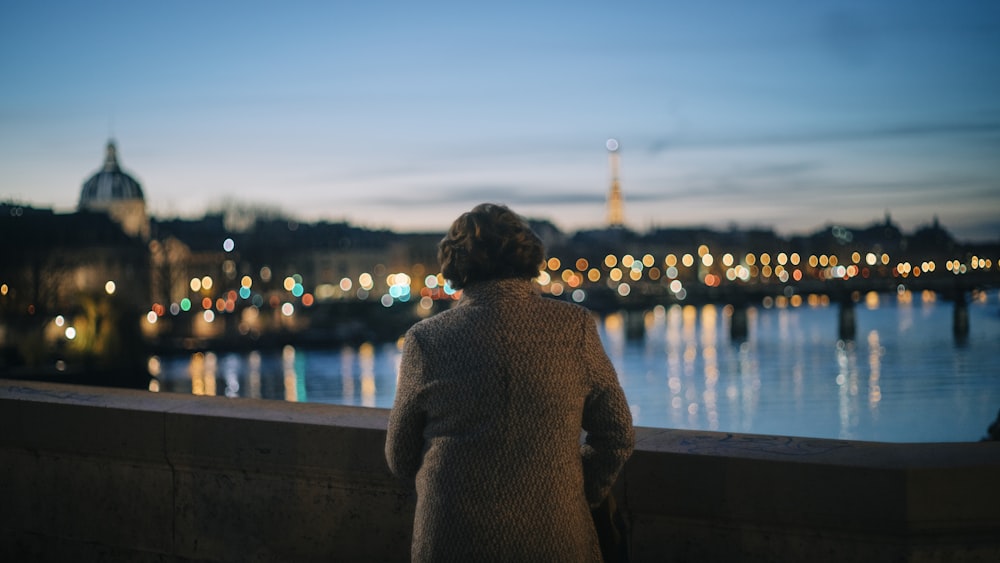 person in brown coat standing on dock during night time