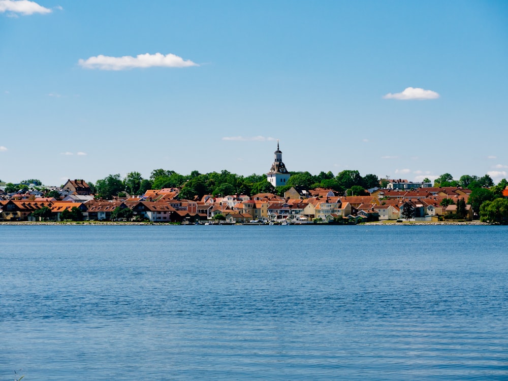 body of water near green trees and houses under blue sky during daytime