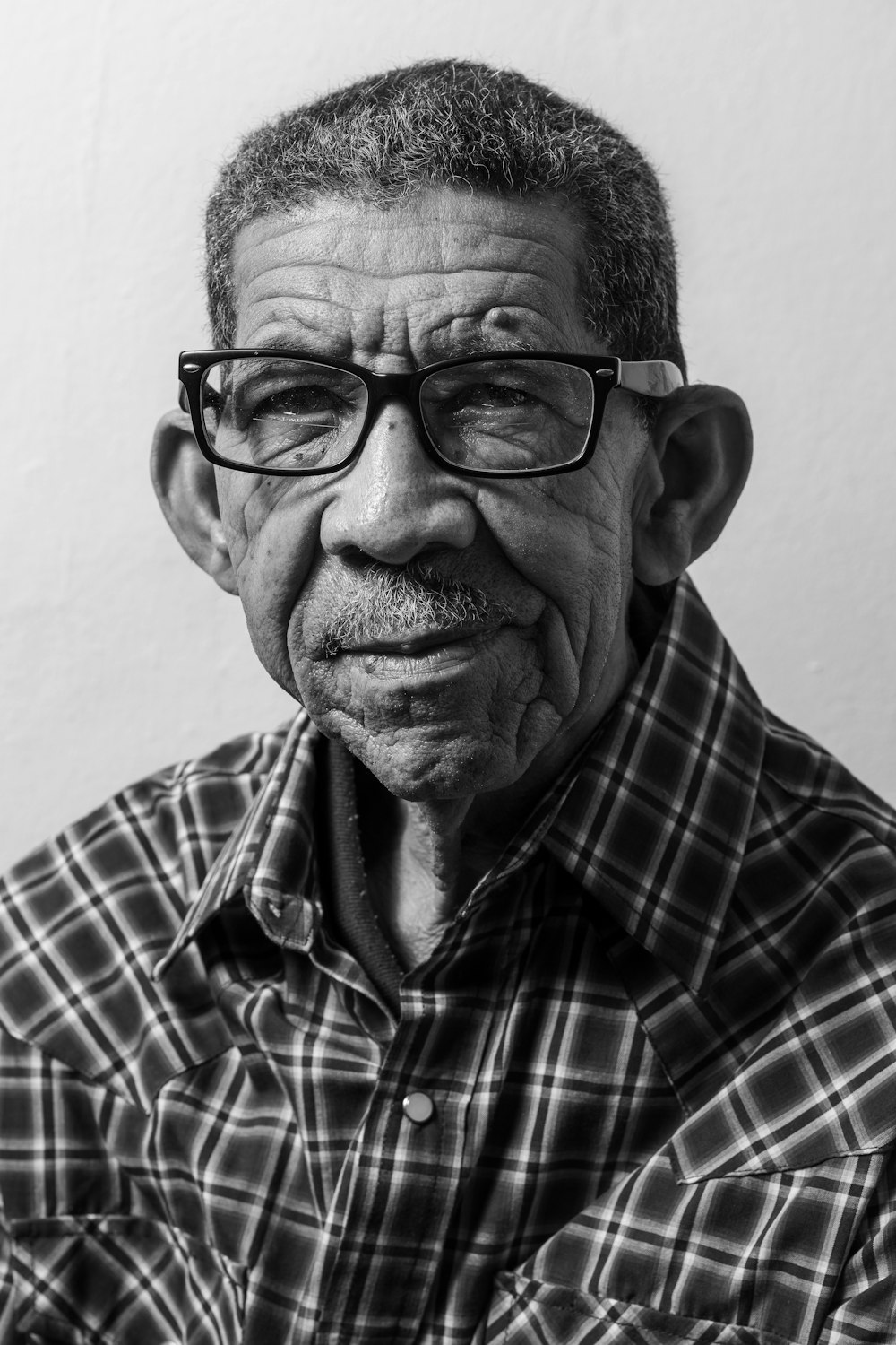 man in black framed eyeglasses and brown white plaid button up shirt