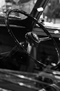 A sepia-toned close-up of a weathered vintage car steering wheel catching soft sunlight