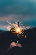 person holding sparkler in grayscale photography