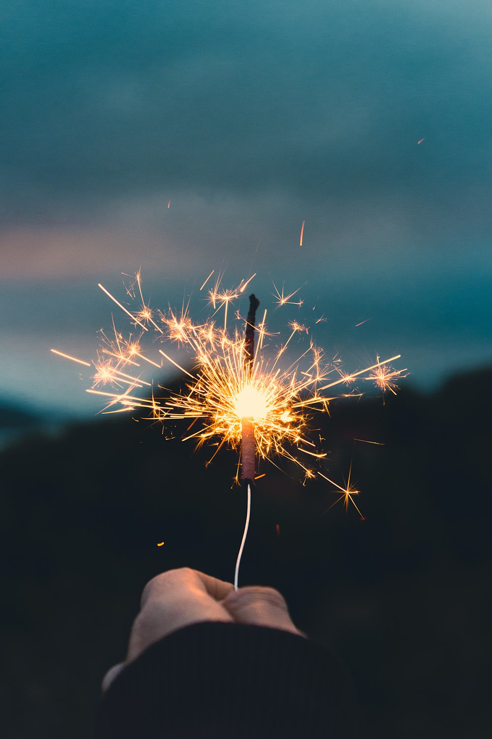 person holding sparkler in grayscale photography