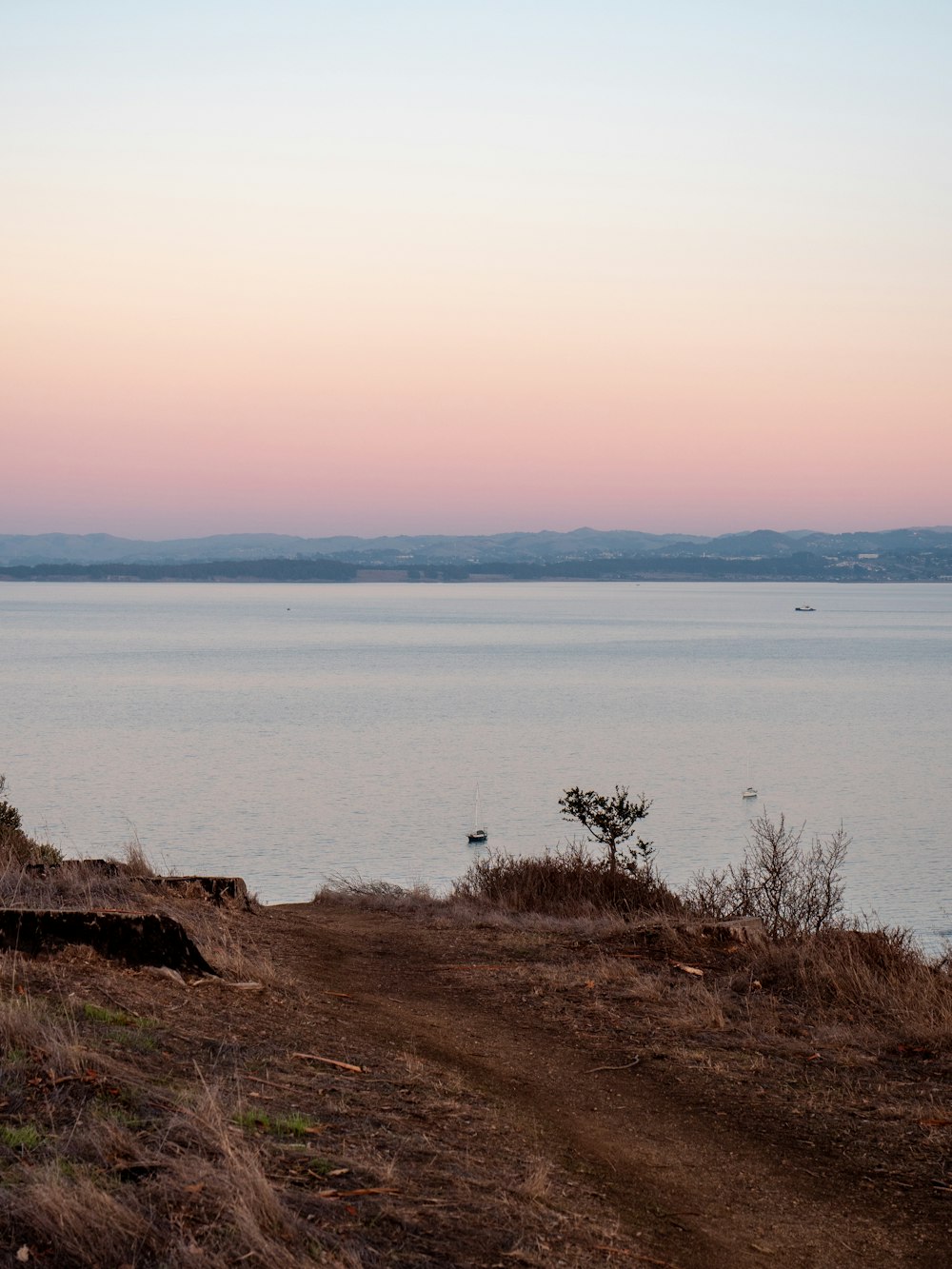 brown rocky mountain beside body of water during daytime