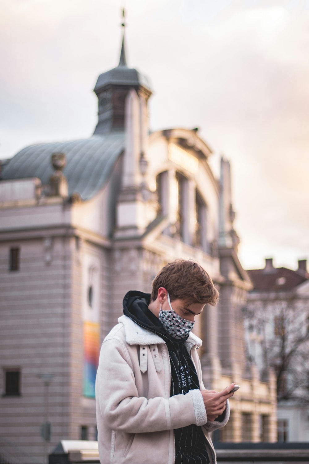 woman in white coat standing near building during daytime