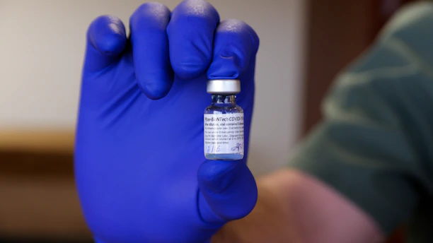 Close-up of hands holding a vital medical supply package with a subtle insurance card in the background