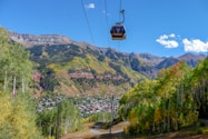 cable car over green trees and mountain during daytime