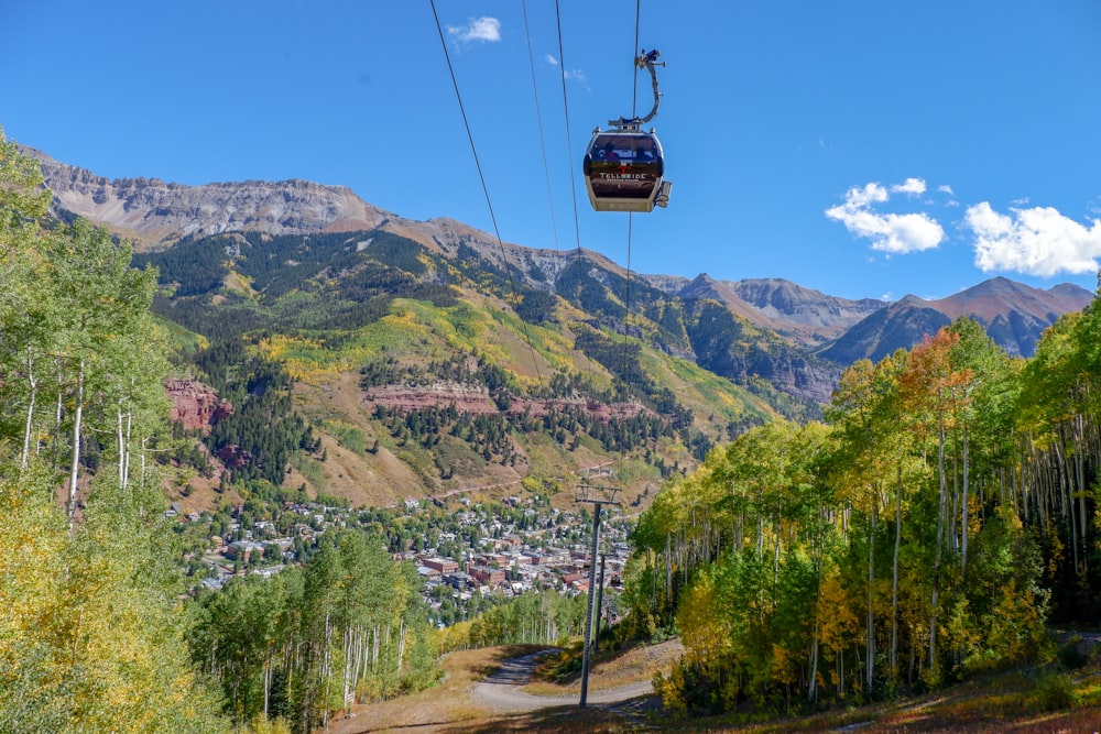 cable car over green trees and mountain during daytime