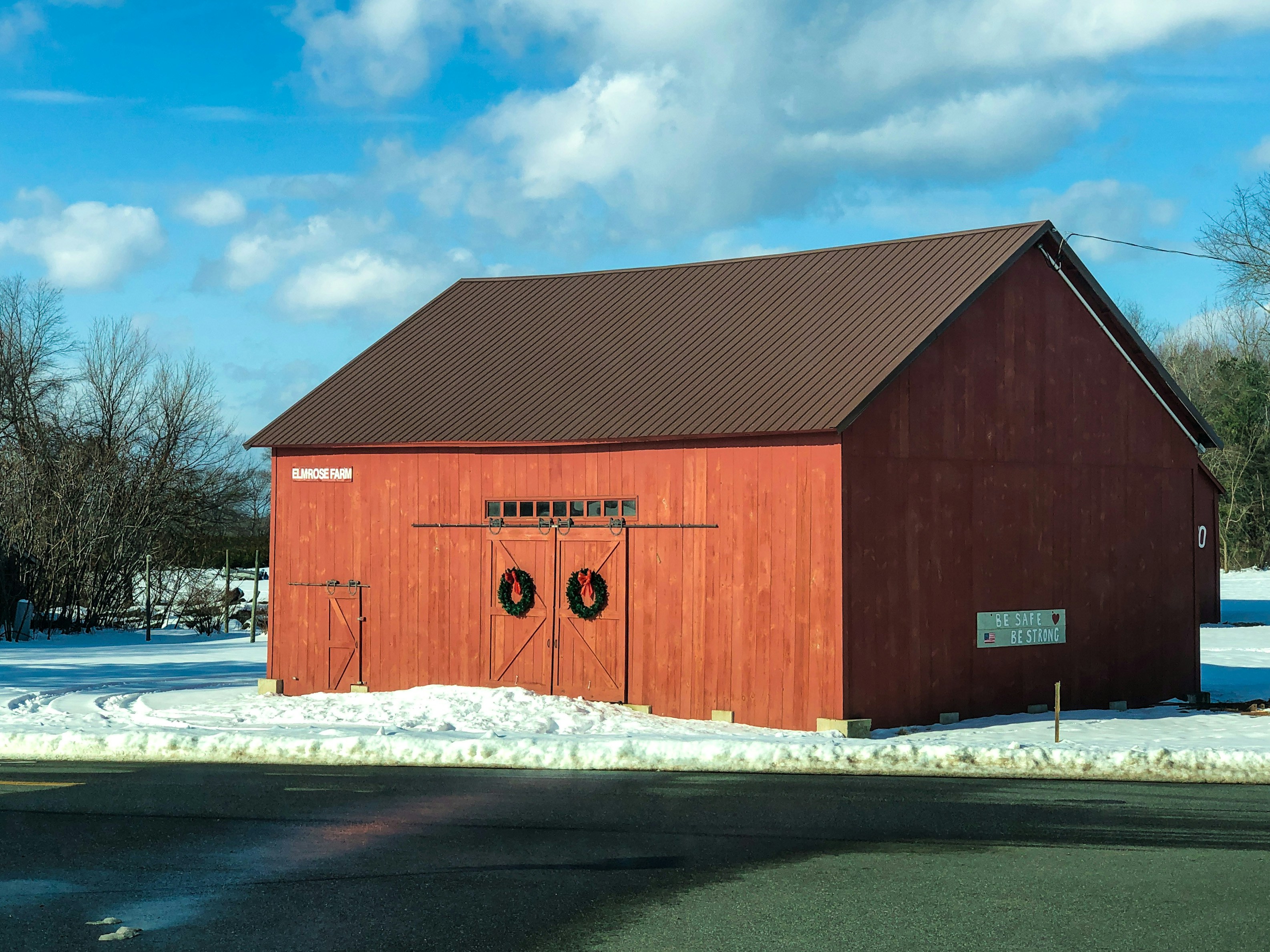 red wooden barn under white clouds and blue sky during daytime