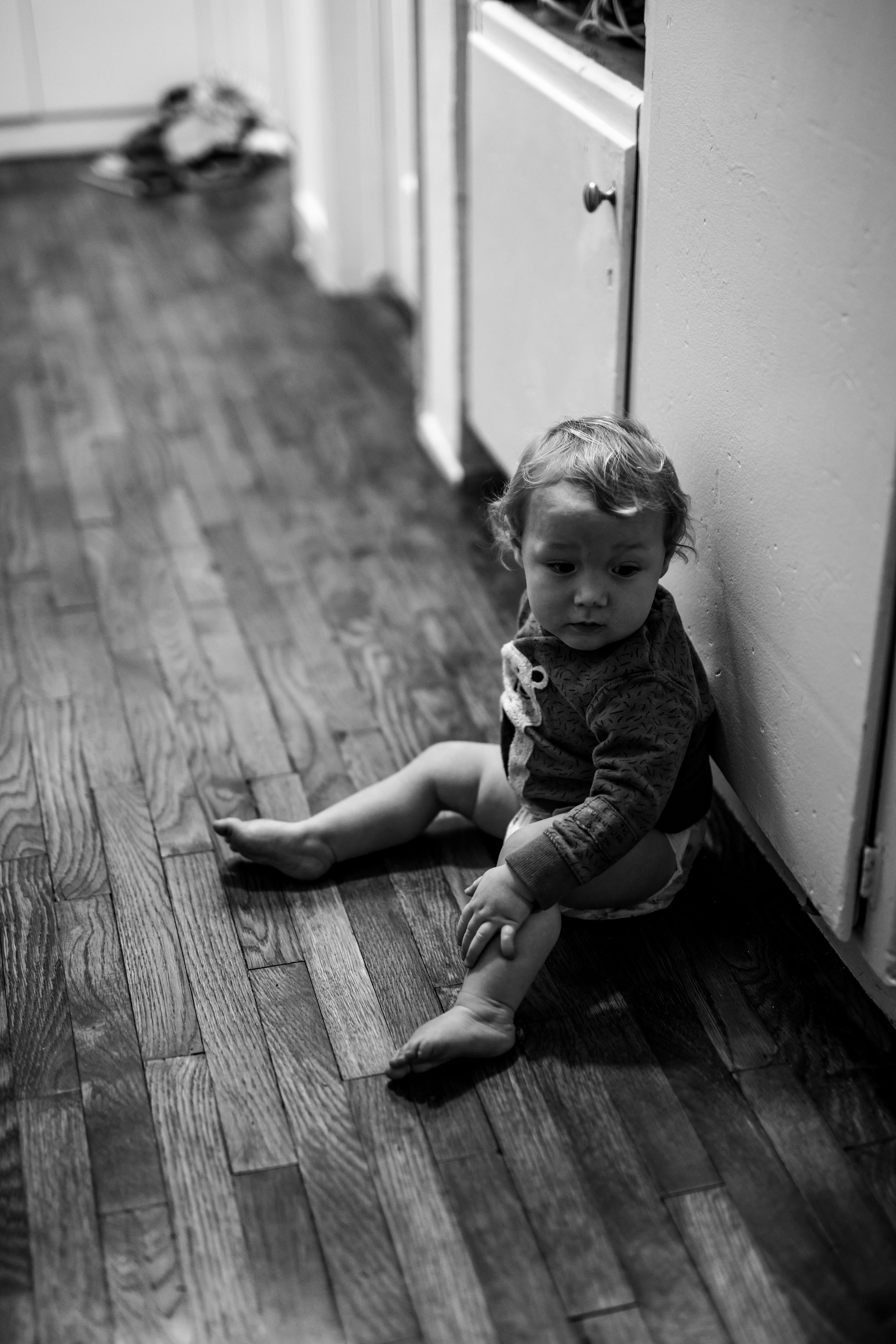 grayscale photo of child in onesie lying on floor