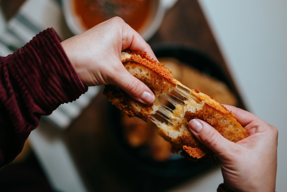 person holding bread with ham and cheese