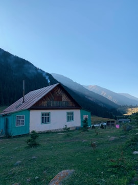 A rustic mountain villa surrounded by pine trees with smoke gently rising from a pellet stove chimney.