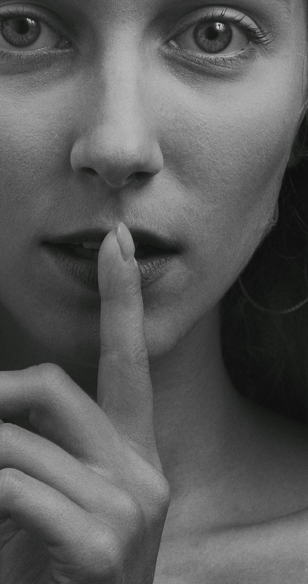 grayscale photo of woman with finger on her lips