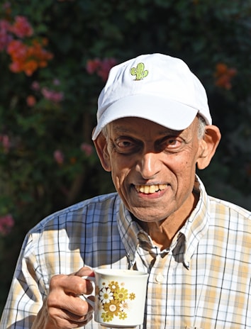 A joyful elderly person smiling while enjoying a cup of coffee.