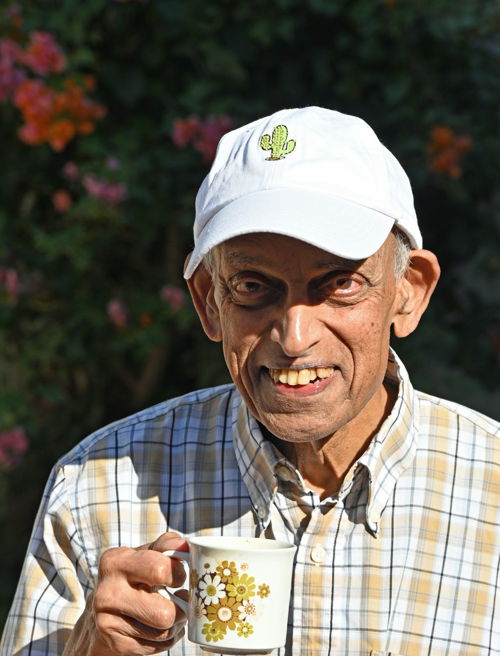 man in white cap and blue and white plaid button up shirt holding white ceramic mug