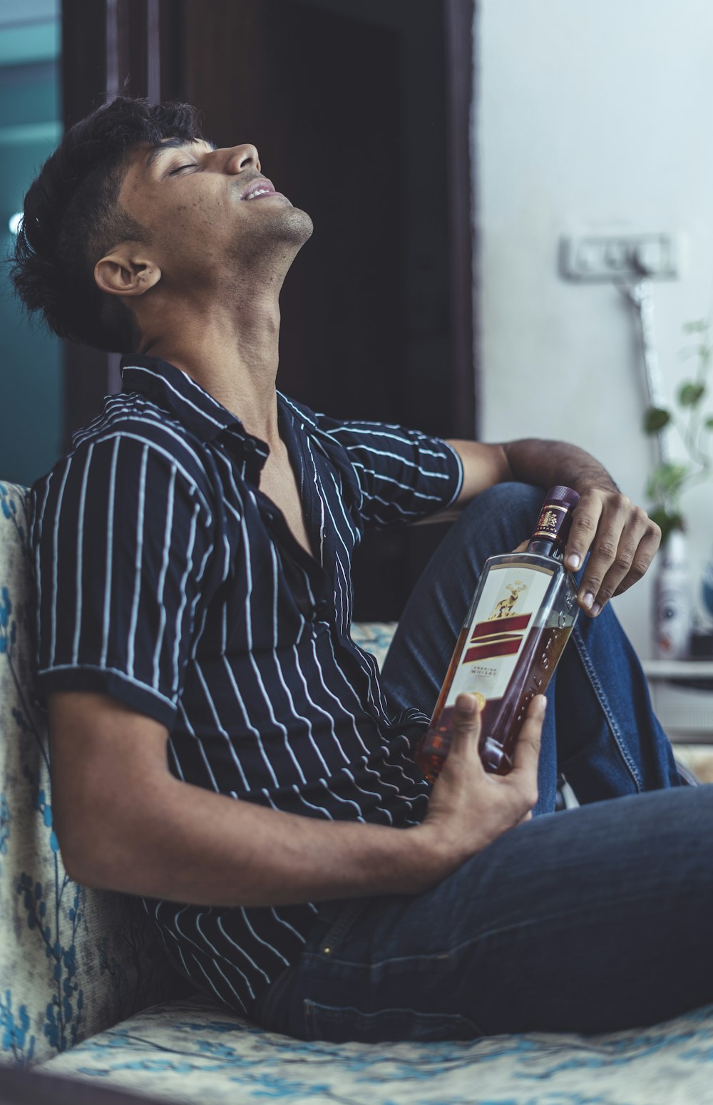 homem na camisa polo preta e branca listra segurando garrafa