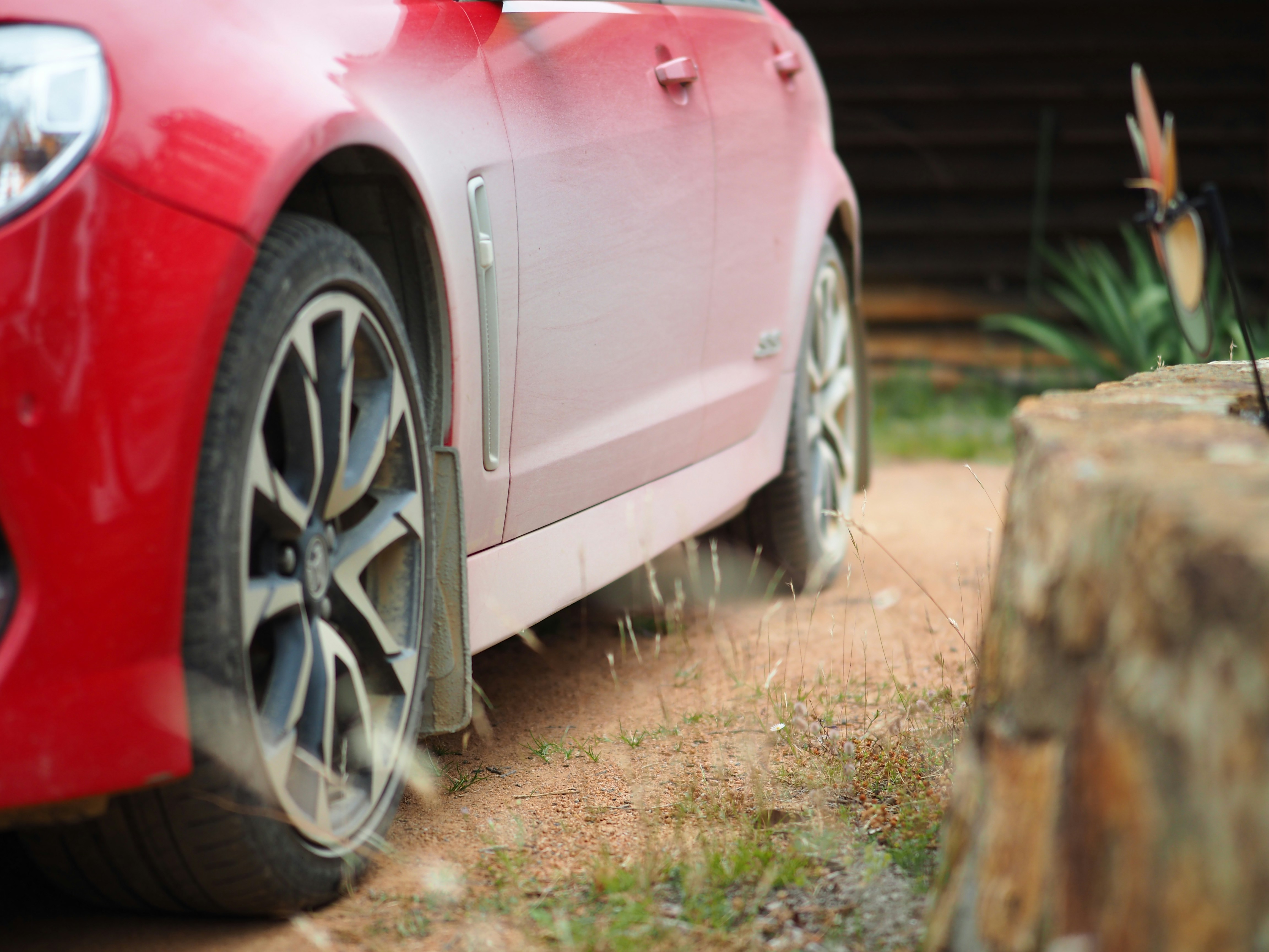 red car parked near brown wooden fence