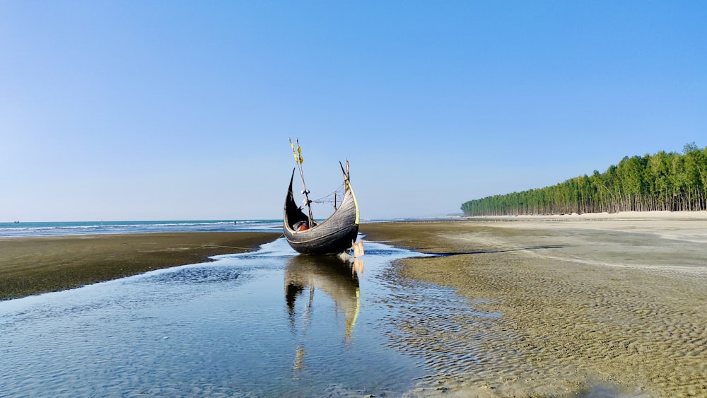 black boat on sea shore during daytime