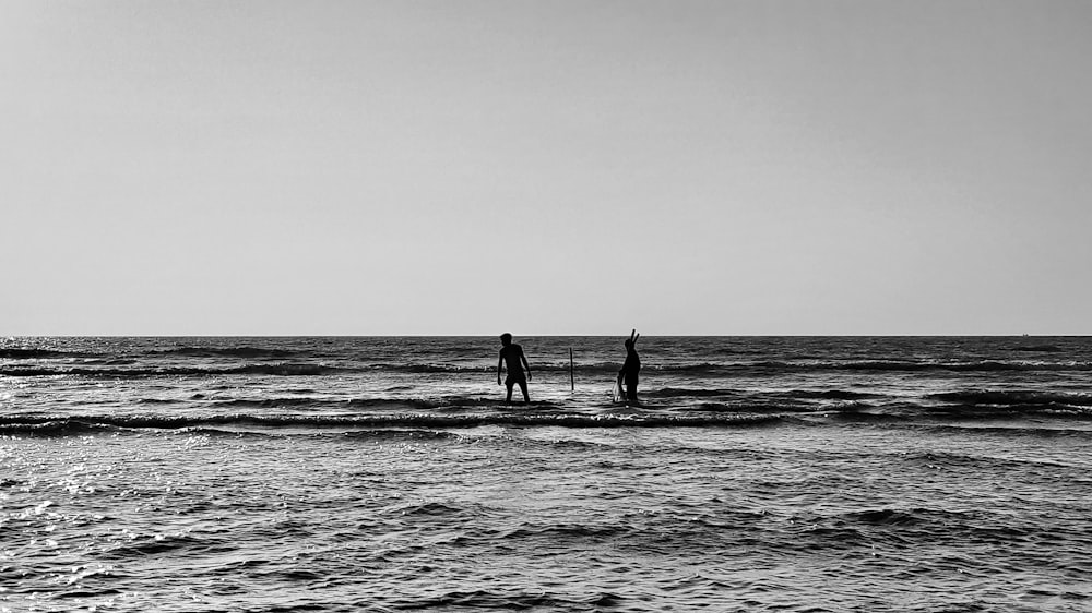 silhouette of 2 person walking on the beach during daytime