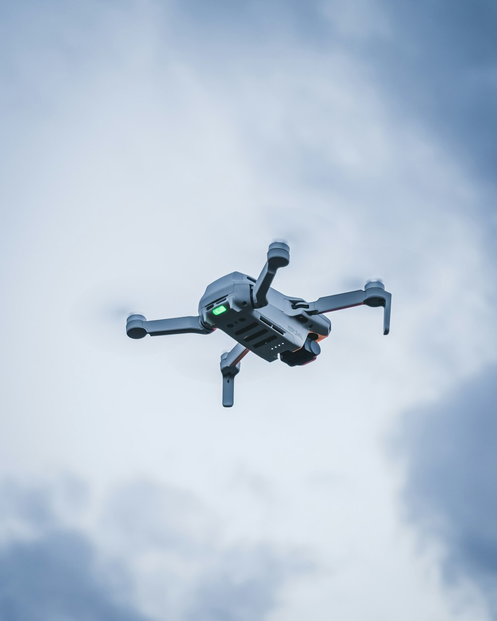 green and black drone flying under white clouds during daytime