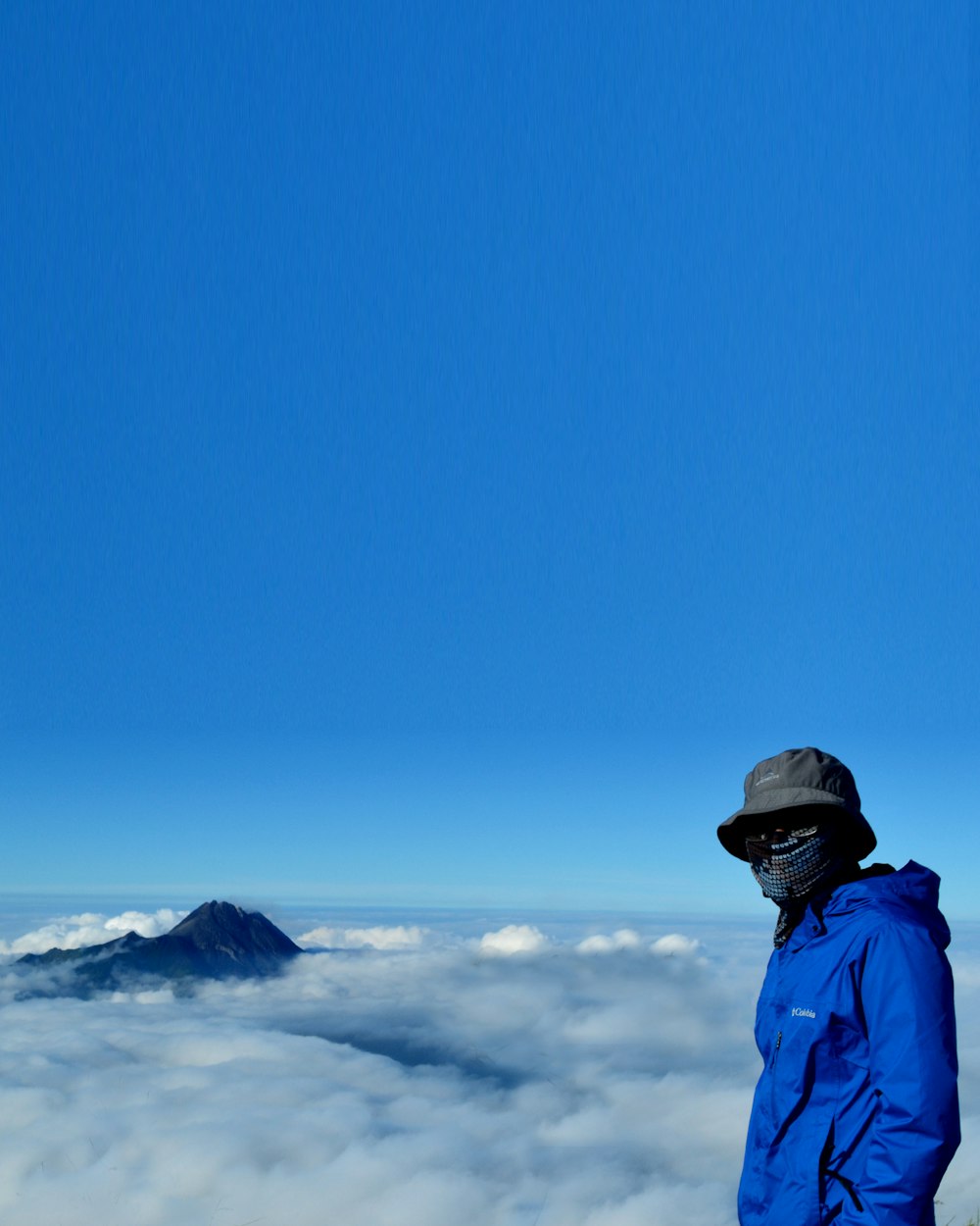 man in blue jacket and black cap standing on snow covered ground during daytime