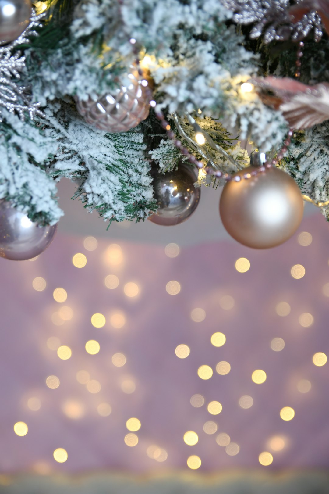 green pine tree with white snow flakes and white and yellow bokeh lights