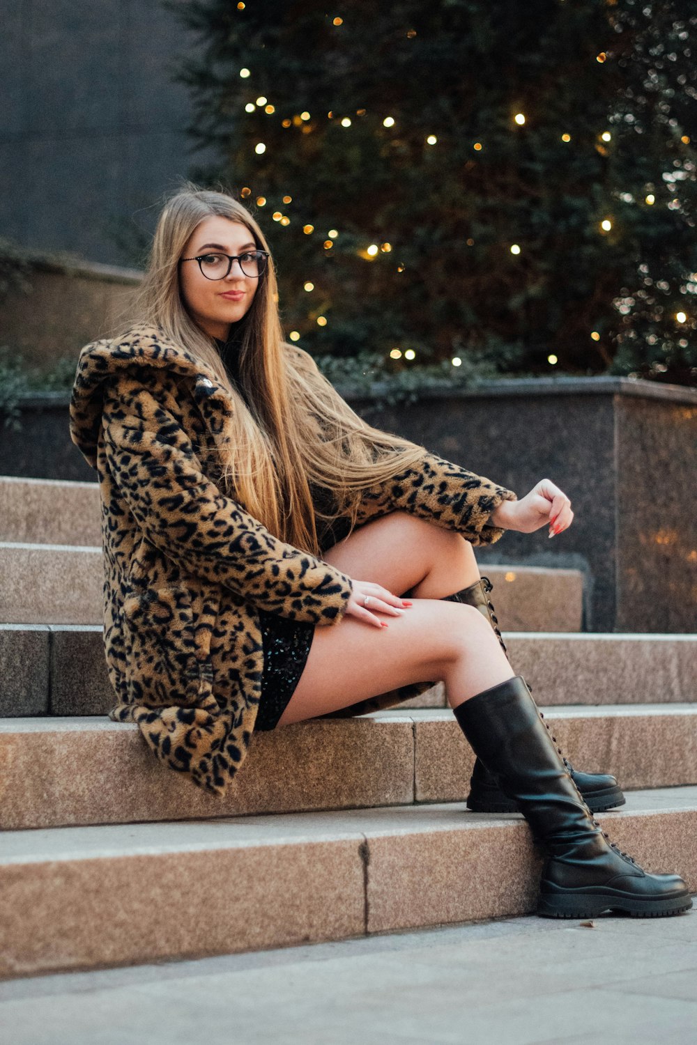 woman in brown leopard print coat sitting on concrete stairs