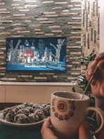 white ceramic mug near black flat screen tv