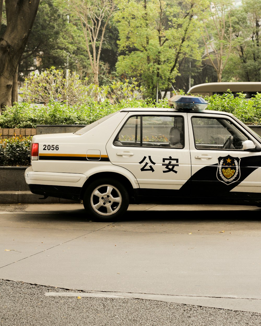 昼間の道路を走る黒と白のパトカー