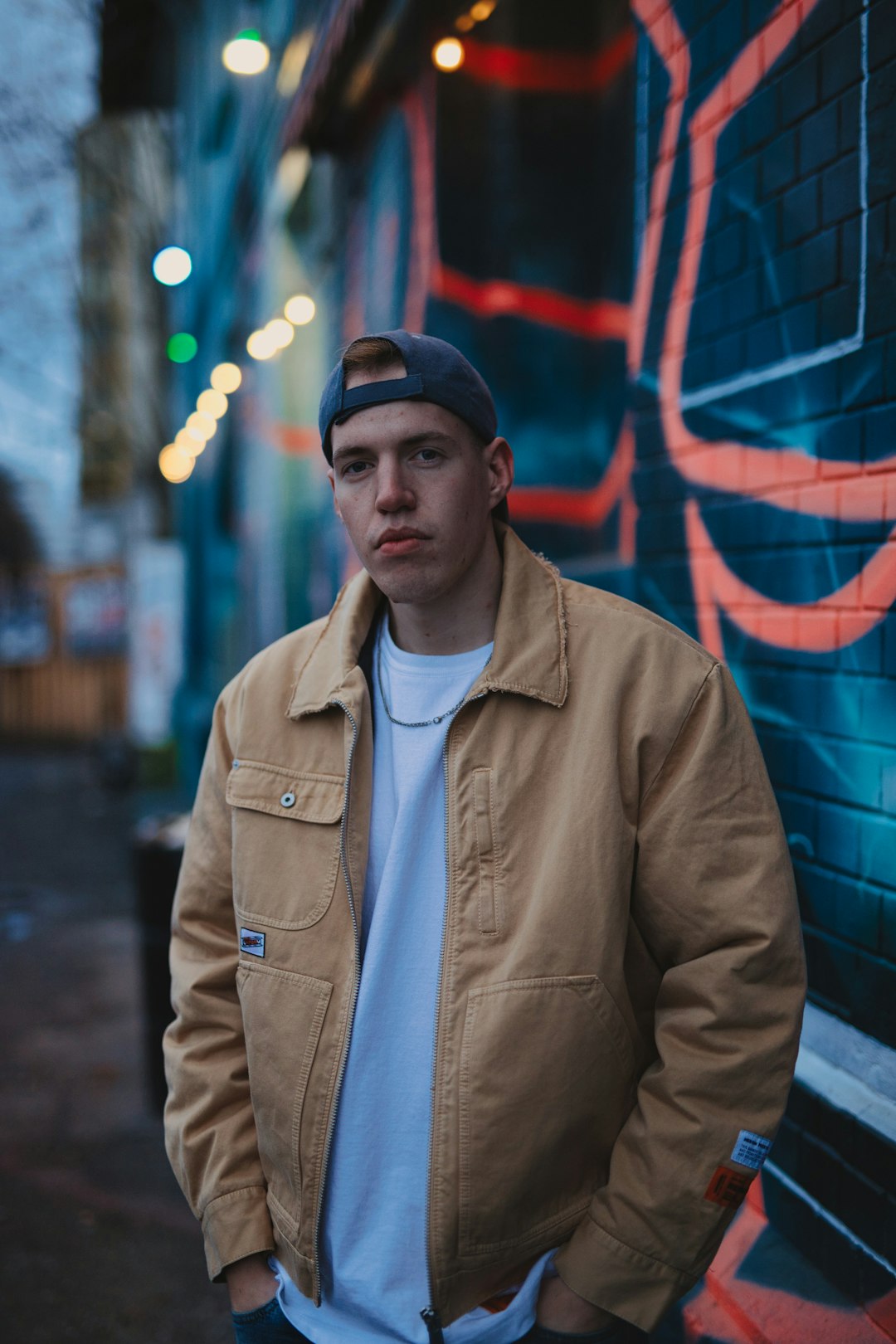 man in brown jacket standing near red wall