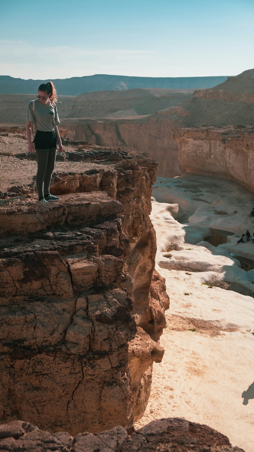 uomo in camicia bianca in piedi sulla formazione rocciosa marrone durante il giorno