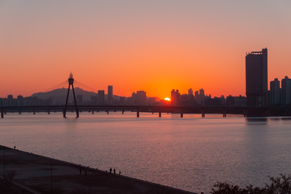 silhouette of person walking on bridge during sunset