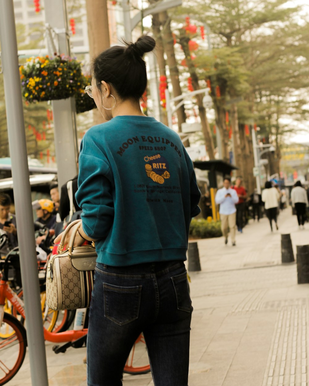 man in blue long sleeve shirt and blue denim jeans standing on sidewalk during daytime