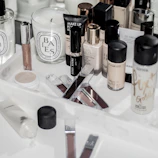 Assorted makeup bottles, tubes, and a scented candle on a white marble tray