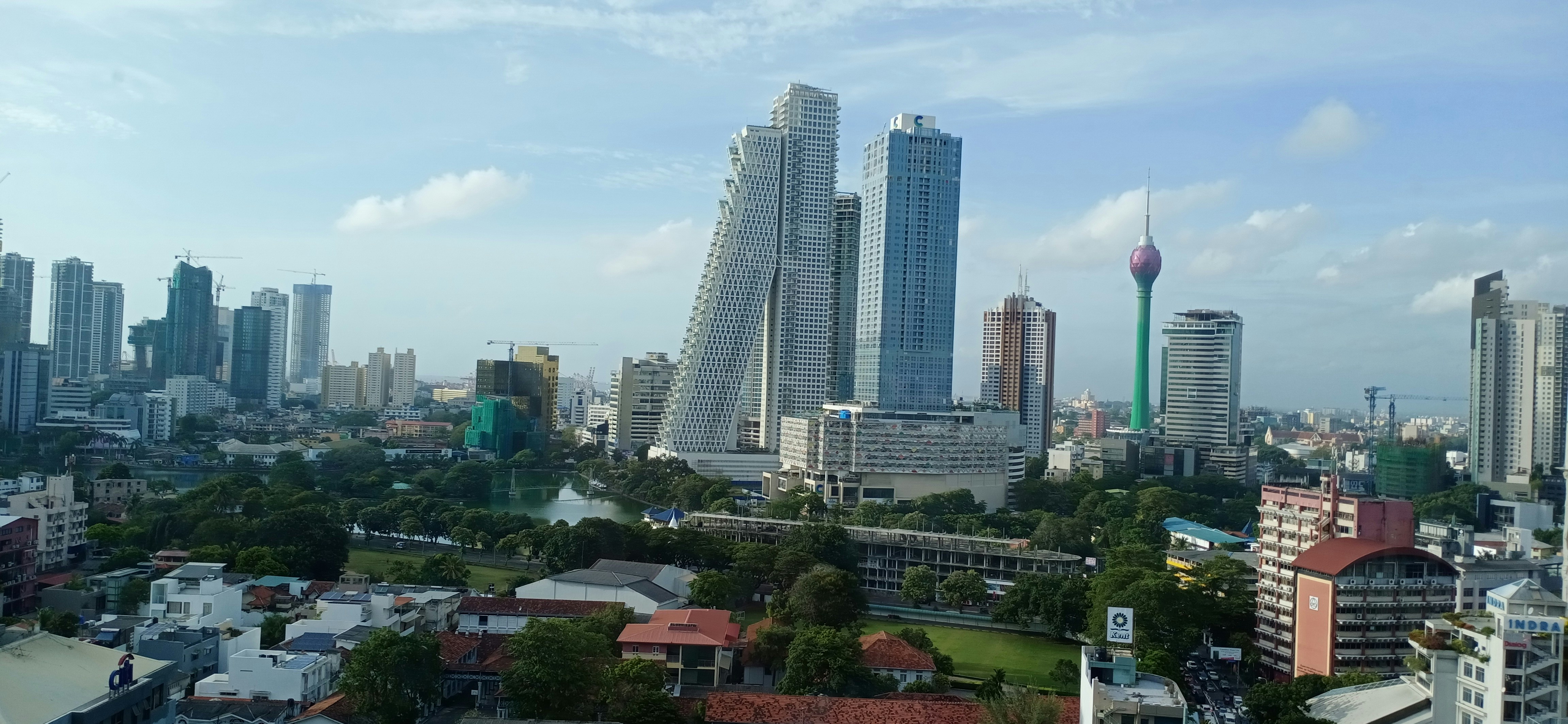 Colombo city skyline at dusk, modern glass towers with Lotus Tower, busy urban streets with lights