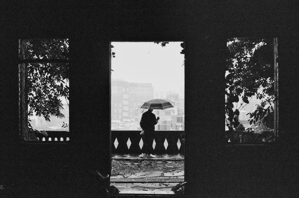 grayscale photo of person holding umbrella