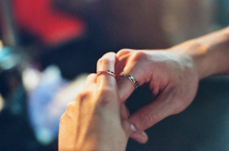 A close-up of a couple’s hands exchanging a small velvet box with a delicate necklace inside, symbolizing love and care.