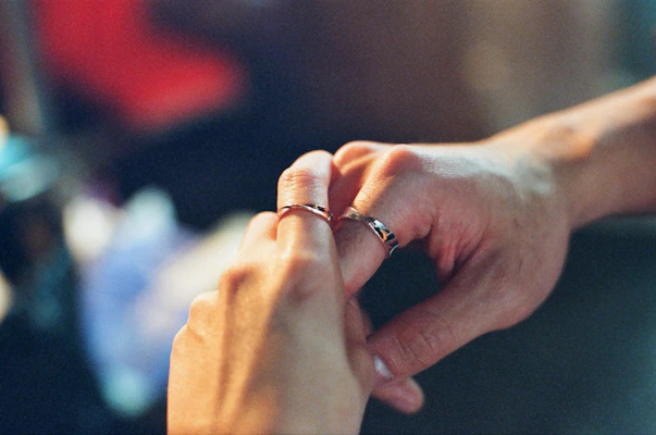 A close-up of a couple’s hands exchanging a small velvet box with a delicate necklace inside, symbolizing love and care.