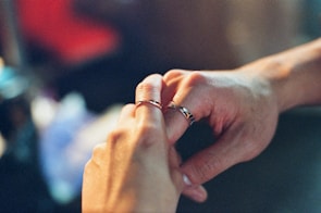 An intimate close-up of hands exchanging wedding rings, highlighting delicate details.