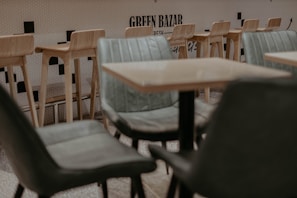 Cozy seating nook with black velvet chairs and a small table under a neon green ghost sign
