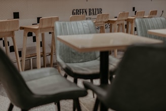 Cozy seating nook with black velvet chairs and a small table under a neon green ghost sign