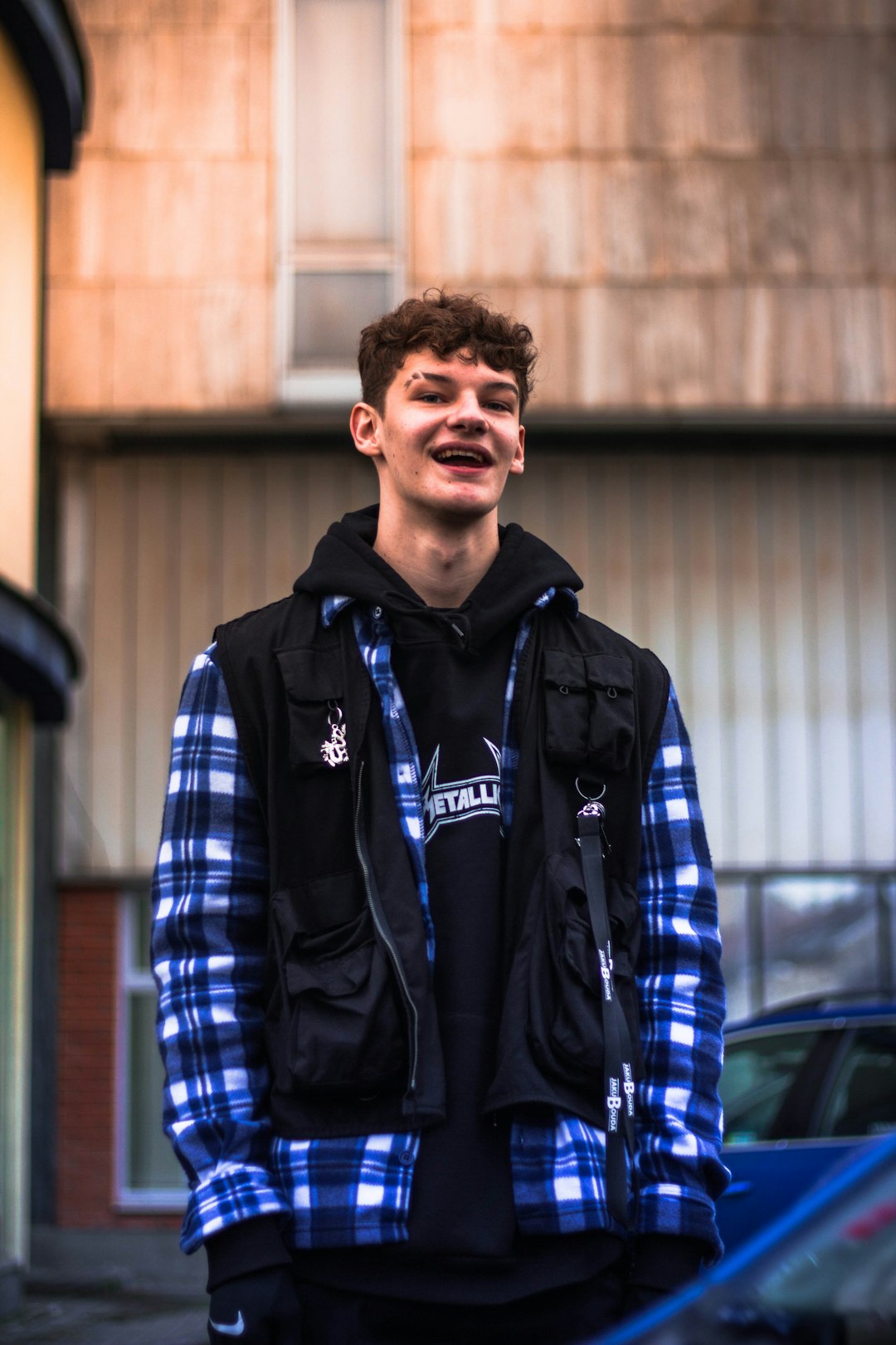 man in blue and black zip up jacket standing near blue car during daytime